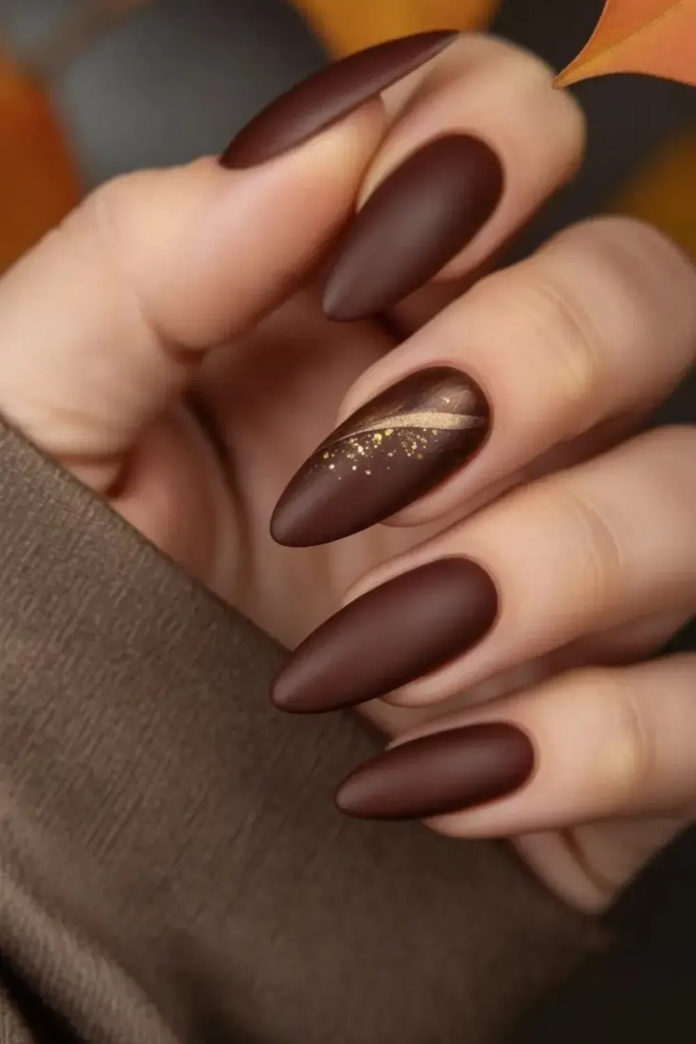 Matte brown fall nails with a golden leaf design on one nail, featuring a warm autumn vibe with a touch of elegance