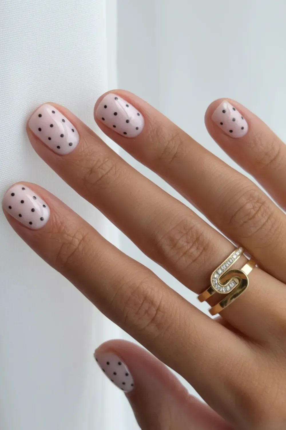  Soft nude short nails with small black polka dots for a simple, cute, minimalist design.