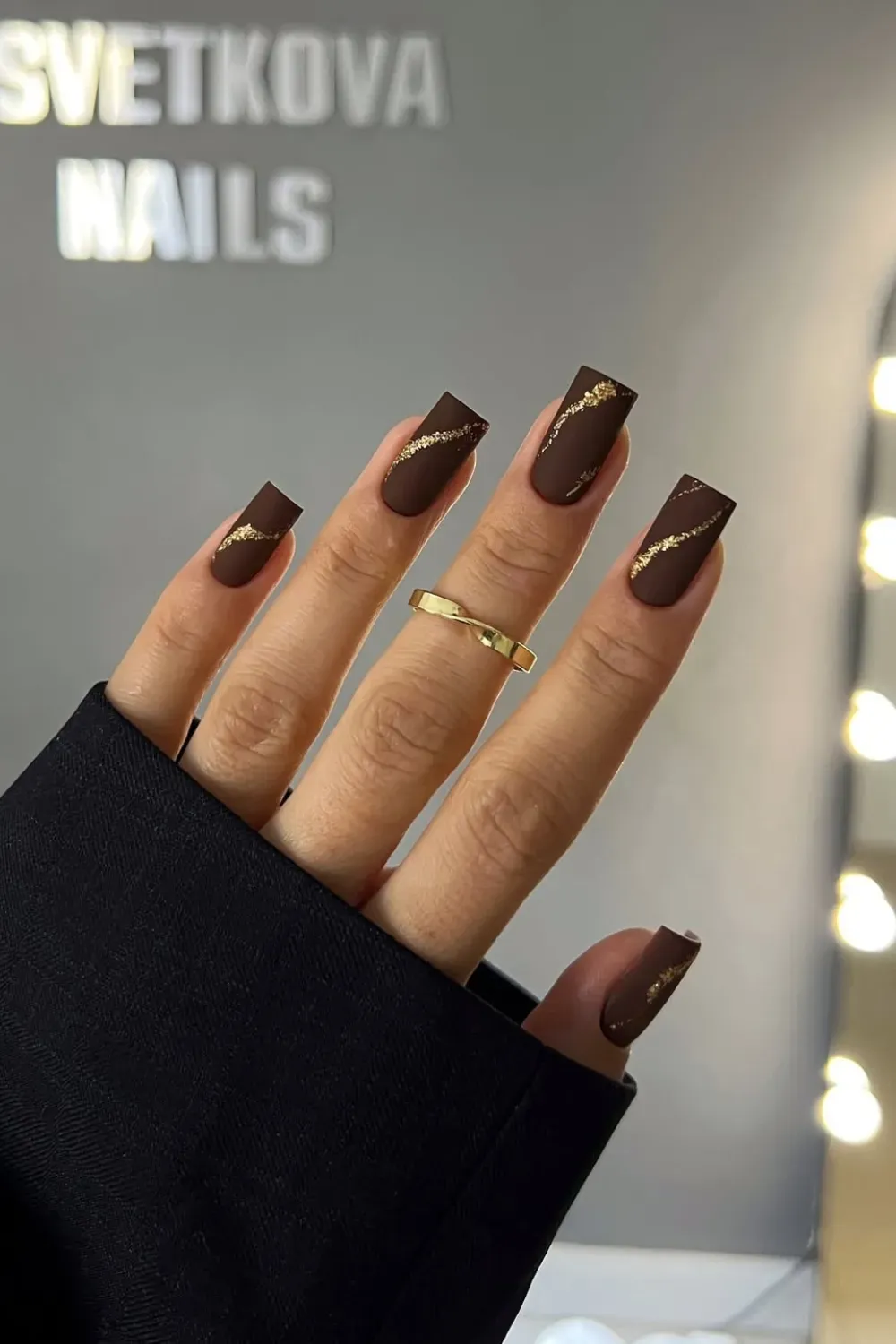 Brown Matte Nails with Gold Accents - A close-up of matte brown nails with delicate gold accent lines, showcasing a stylish fall nail design