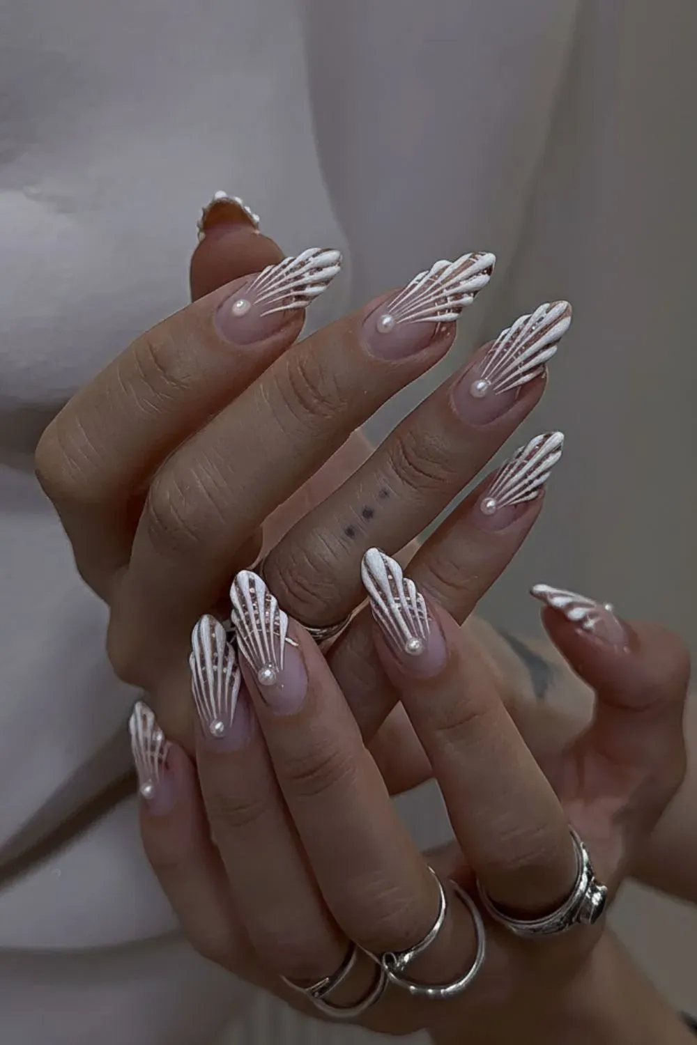 White chrome nails with intricate geometric patterns and pearls. 4. Chrome French Tips with Glitter