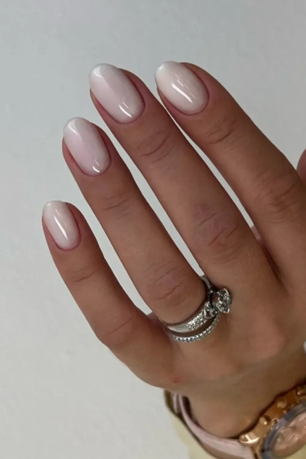 Classic Short Almond Milky Nails for Quiet Luxury - Close-up of short, almond-shaped gel nails in a sheer white milky polish with a subtle cuticle gradient.