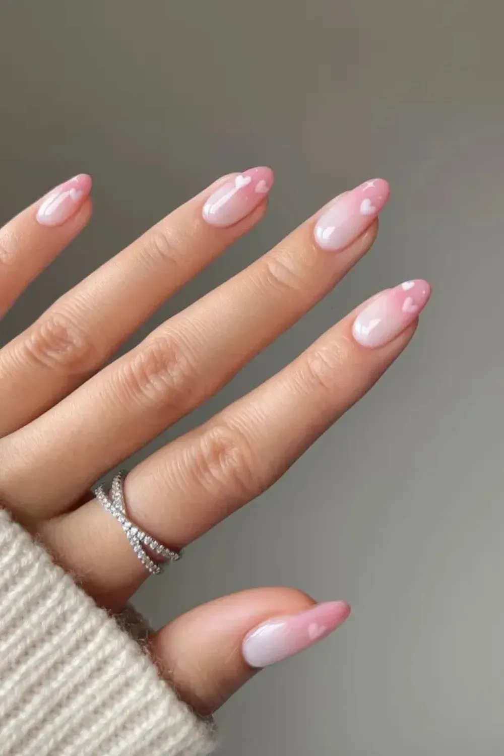 Romantic Ombre Pink Milky Nails with Heart Art - Long almond-shaped nails with a pink and white ombre milky base, accented with small white hand-painted heart designs.