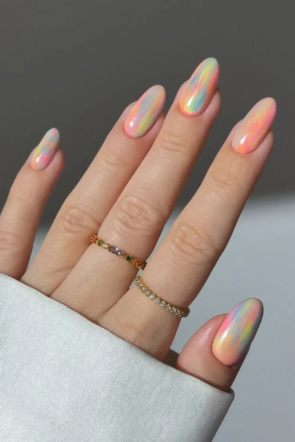 Iridescent Swirl Milky Abstract Nails - Almond-shaped nails featuring a milky base with abstract, iridescent swirls of bright pastel colors (pink, yellow, blue).