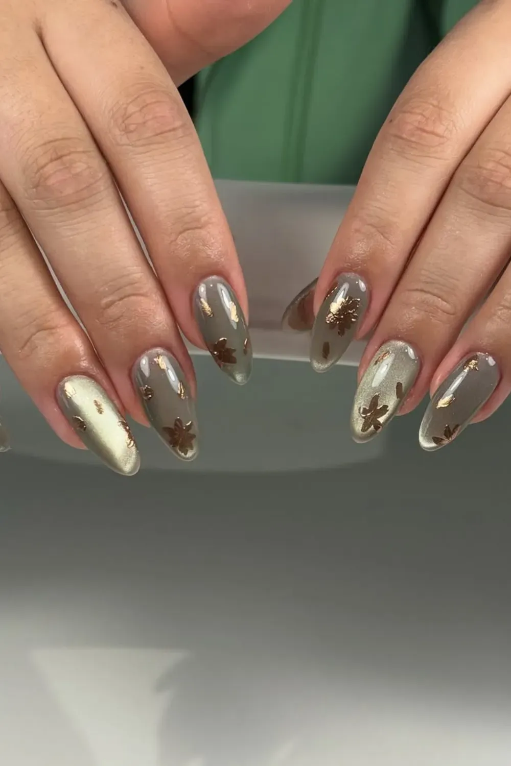 Taupe Metallic Leaf Accent Nails	Almond nails with a shimmery taupe base and delicate, scattered gold leaf foil accents.