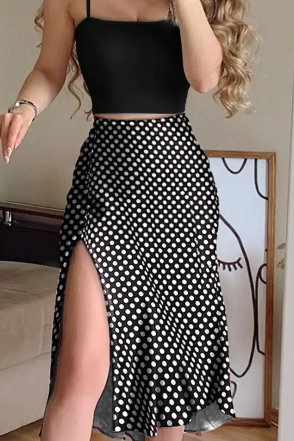 Polka Dot Skirt and Black Crop Top	Woman wearing a high-waisted black midi skirt with small white polka dots, a high side slit, paired with a simple black crop top.