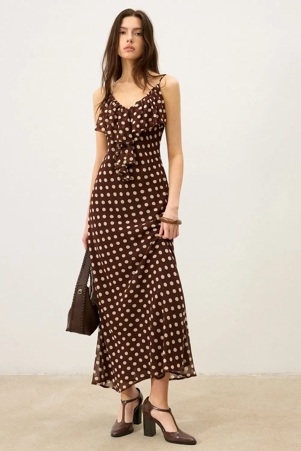 Brown Polka Dot Slip Midi Dress	Woman wearing a chocolate brown midi slip dress with cream polka dots and delicate shoulder straps.