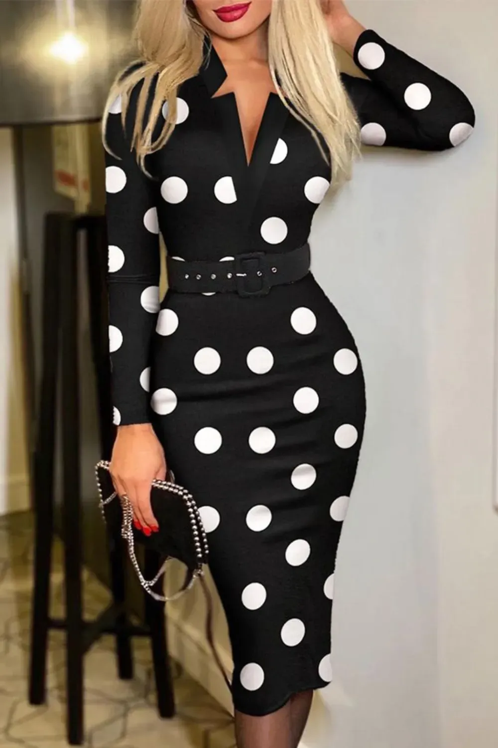 Black Polka Dot Pencil Dress with Belt	Woman wearing a form-fitting black long-sleeve pencil midi dress with large white polka dots, a notched V-neck, and a black belt