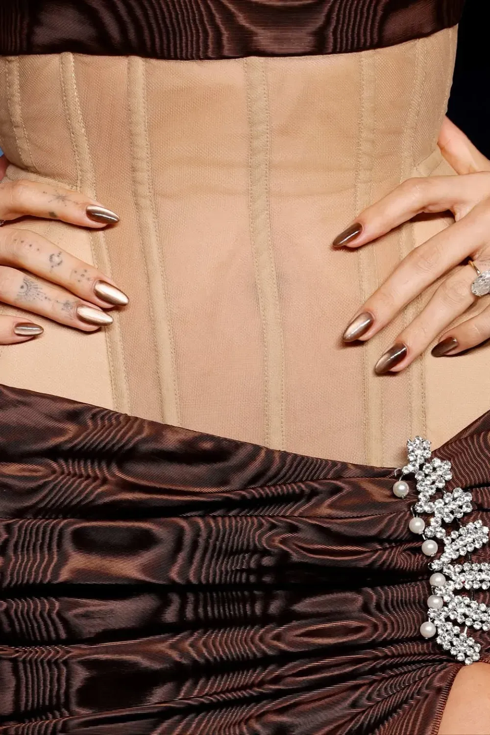 Hailey Bieber Brown Cat Eye Nails	Close-up of Hailey Bieber's almond nails in a high-gloss, shimmering brown cat-eye chrome finish.