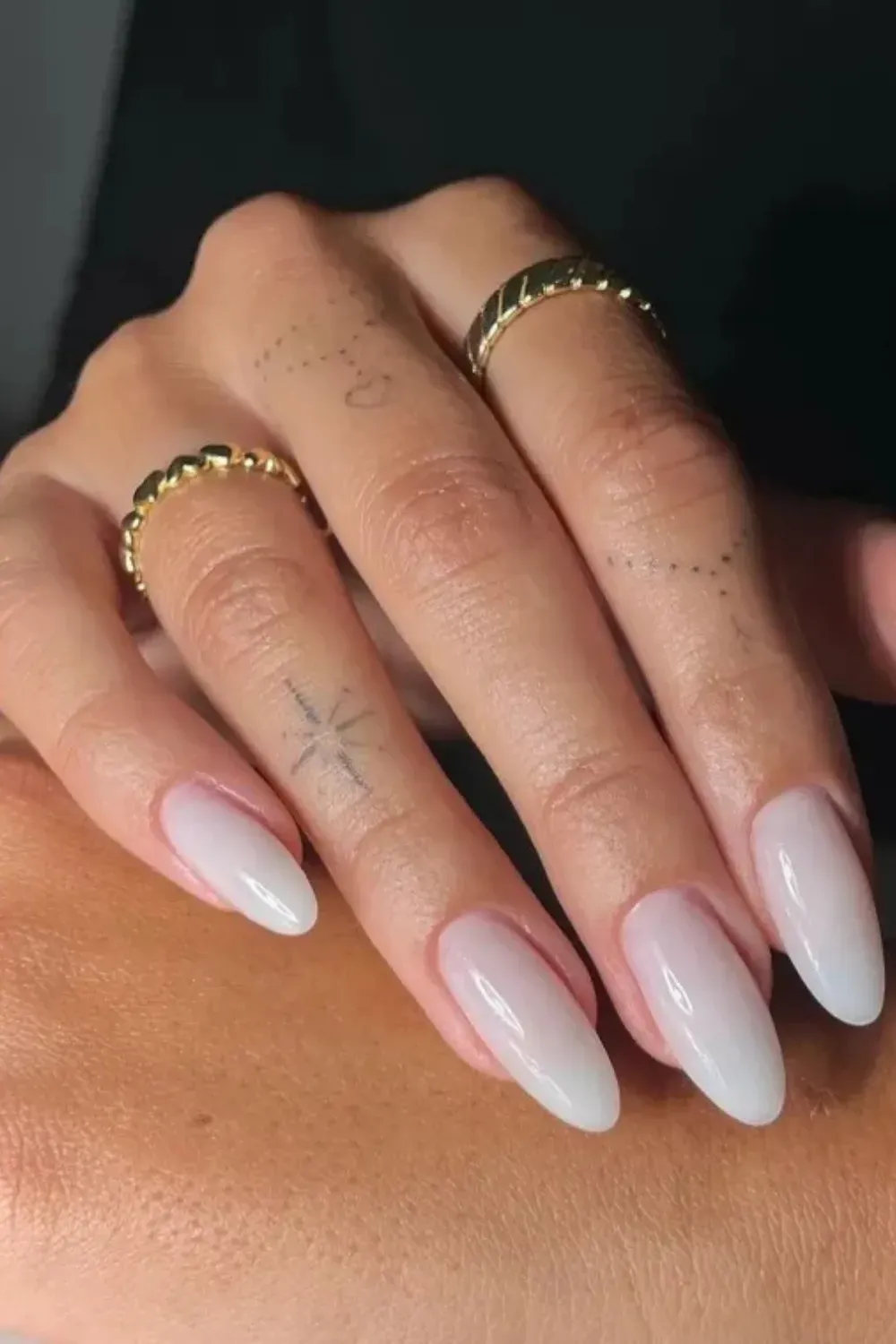 Long Sheer Milky White Almond Nails - Close-up of long, slender almond-shaped nails painted with a high-shine, sheer milky white polish.