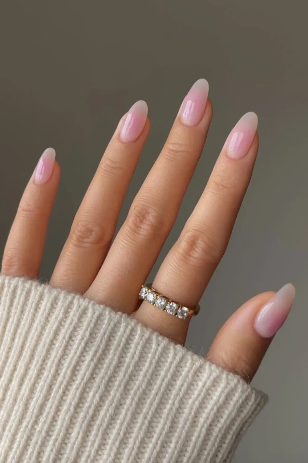 Blushing Ombre Pink Milky Nails - Luxurious Look - Long almond-shaped nails featuring a delicate pink and white blushing ombre milky manicure, styled with a gold five-stone ring.