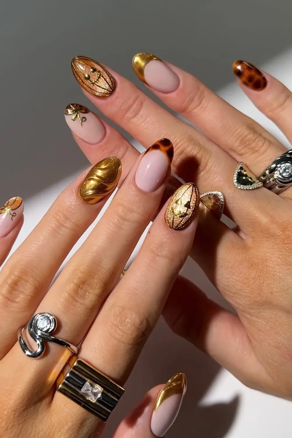 Autumnal Gold Accent French Manicure	Rounded coffin nails featuring a mixed design of nude pink, tortoiseshell tips, and 3D gold accents.