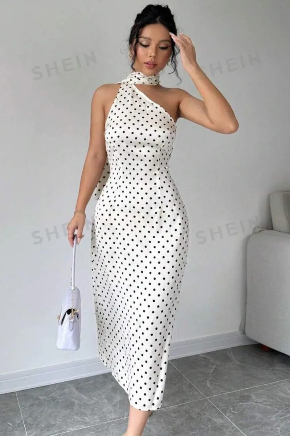 White Polka Dot One-Shoulder Midi Dress with Choker	Woman in a fitted white midi dress with small black polka dots, a one-shoulder design, and an attached neck scarf/choker.