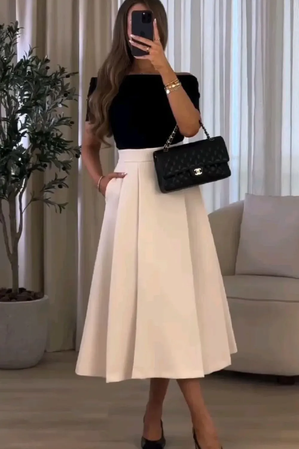 Black and White Formal A-Line Midi Skirt Outfit	Woman wearing a black off-the-shoulder top tucked into a white full A-line midi skirt, styled with black heels and a black quilted Chanel handbag.