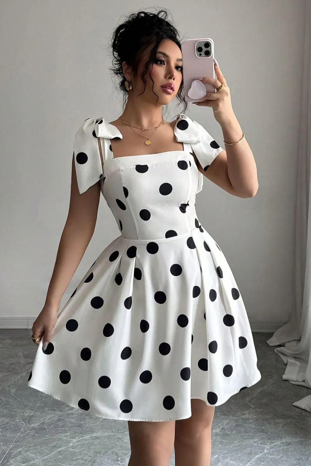 White Polka Dot Mini Dress with Bow Shoulders	Woman in a white A-line mini dress with large black polka dots, a square neckline, and charming bow-tie details on the shoulders.