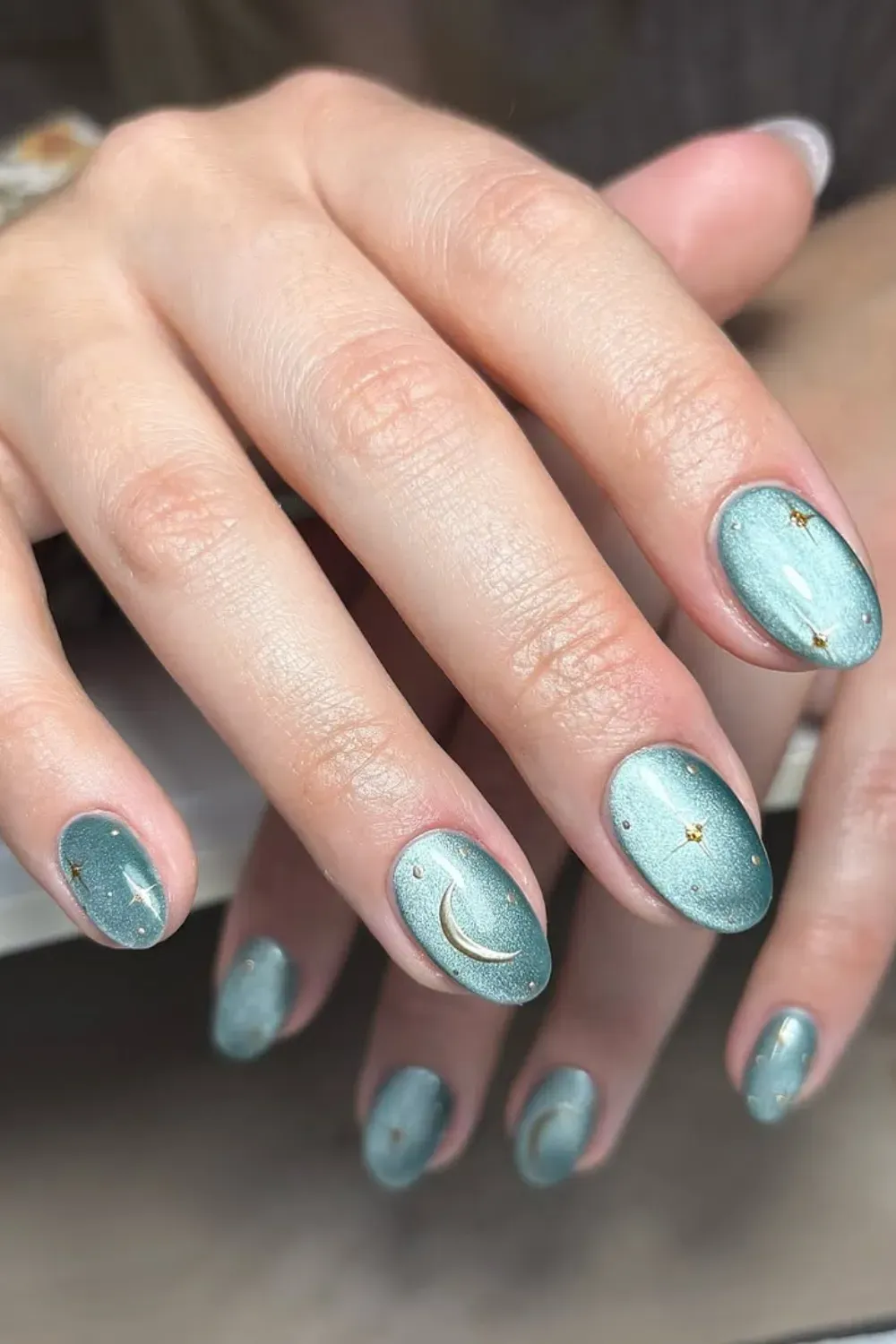 Teal Celestial Cat-Eye Nails	Rounded nails in a soft teal magnetic polish, decorated with tiny gold crescent moon and star decals.