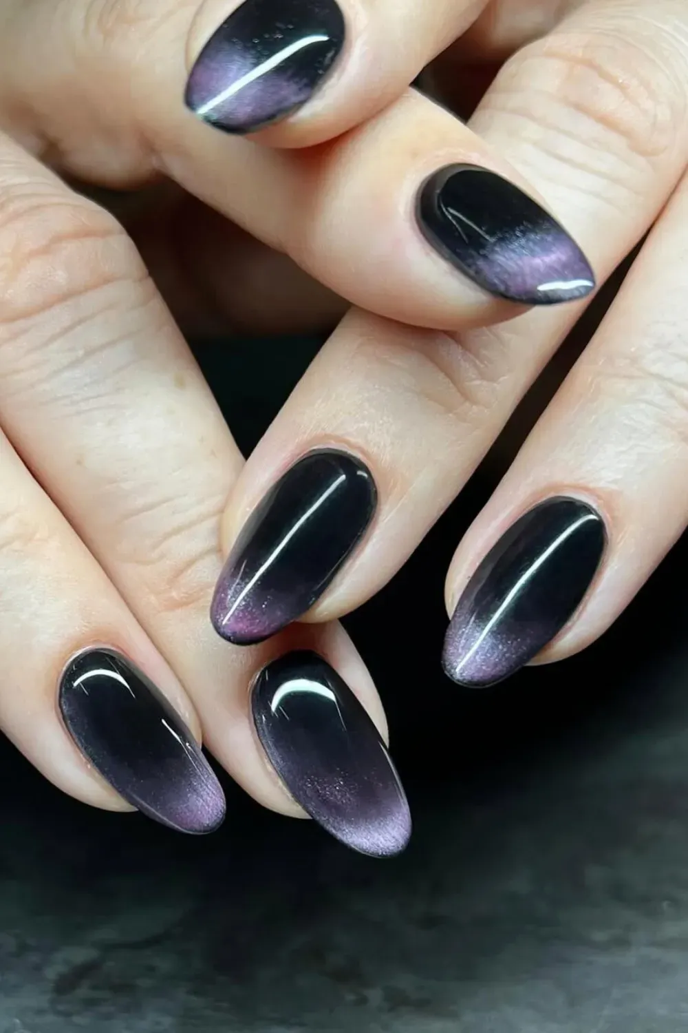 Mesmerizing Purple Cat Eye Ombré: Oval nails with a stunning "cat eye" magnetic effect, transitioning from glossy black at the base to shimmering purple ombré tips
