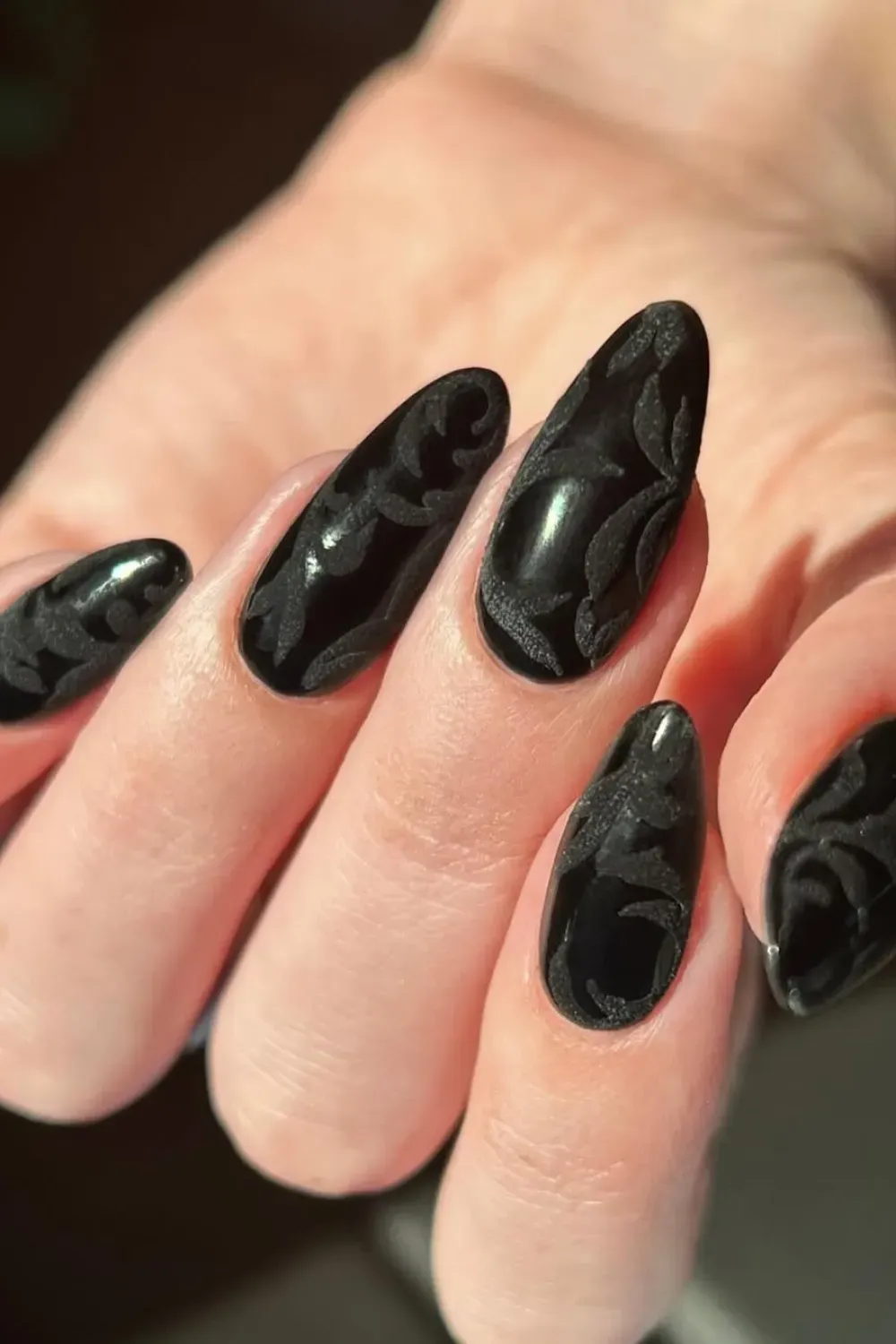 Textured black nails with floral designs - Elegant black nails with textured floral detailing for a bold, artistic nail design.