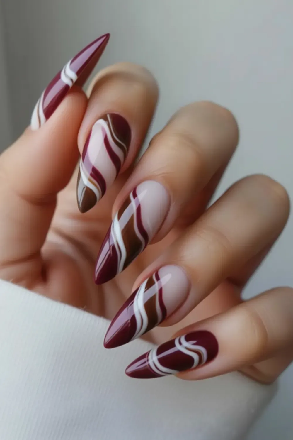 Burgundy & Brown Swirl Nails- Bold brown and burgundy swirl design on pointed nails, combining deep rich colors with a touch of white for a modern, stylish look