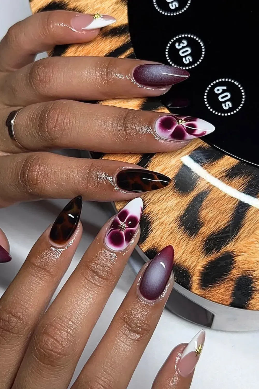 Burgundy Ombré & Floral Accent: Burgundy ombré nails that fade from dark to light, paired with tortoise shell accents and a 3D floral jewel for a romantic, elegant look.