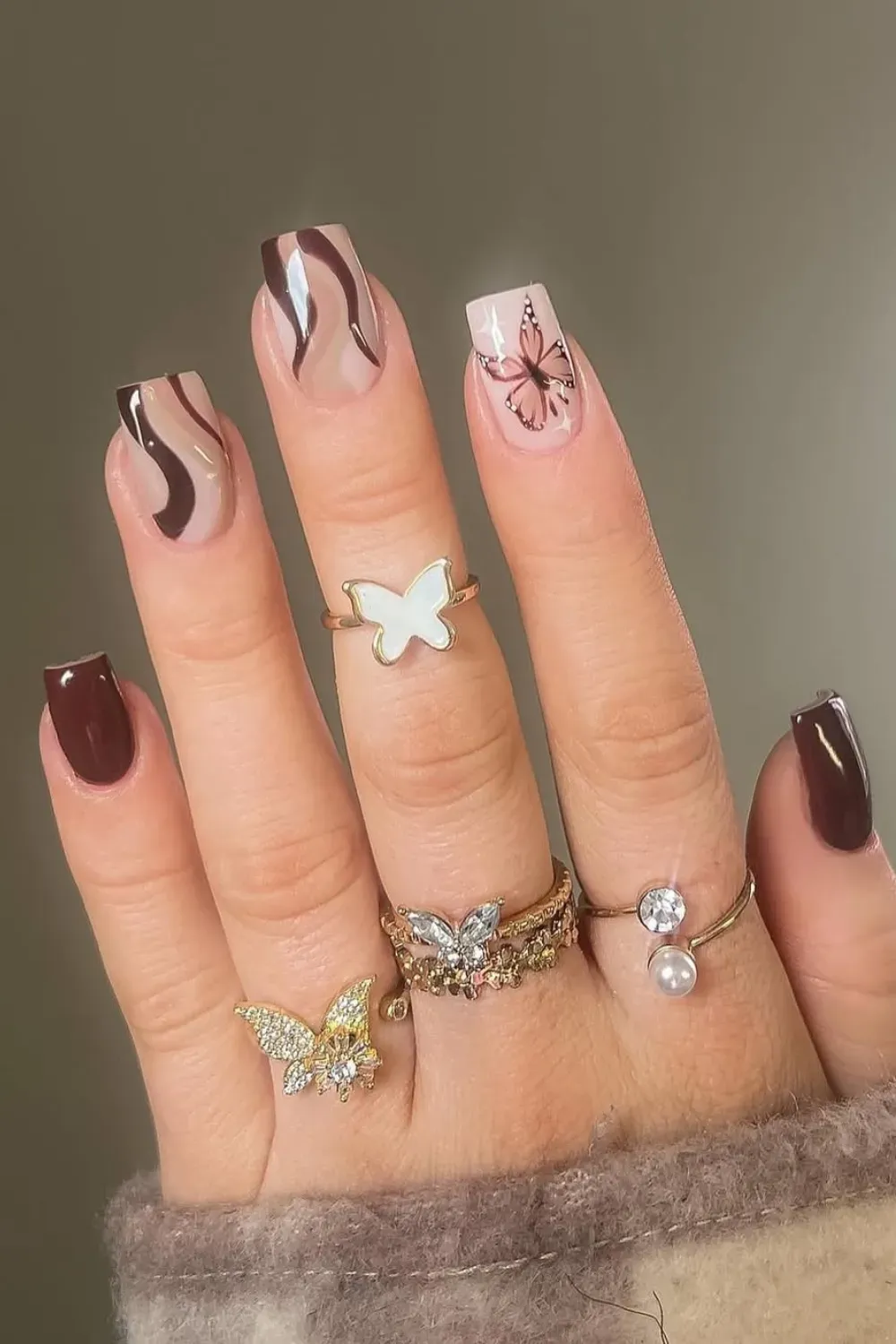 Chocolate brown swirl nails with butterfly accents - Earthy chocolate brown swirl nails with soft butterfly accent for a whimsical, fall-inspired design.
