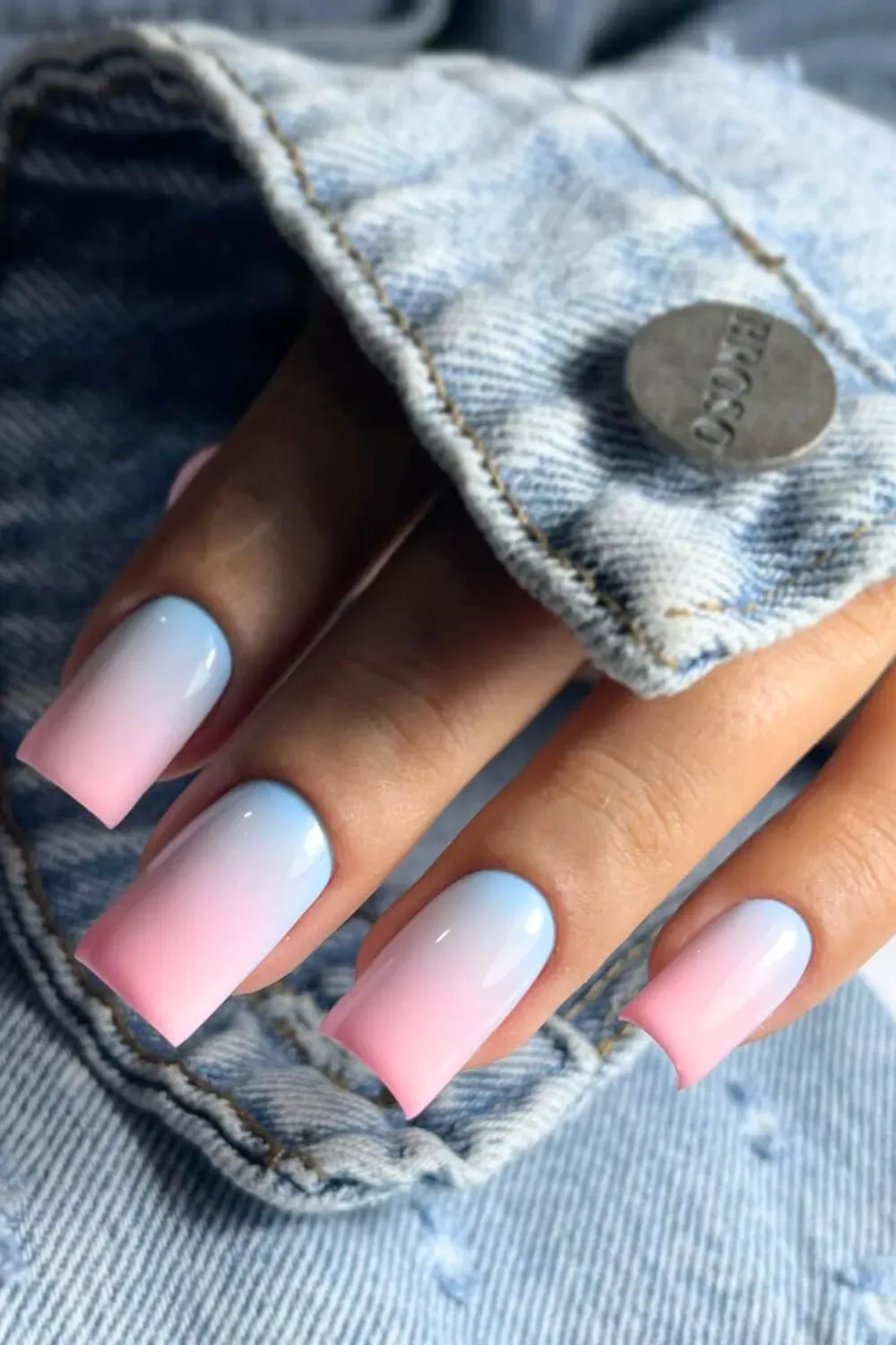 Hand with long square-shaped nails featuring a pink and light blue ombre gradient.