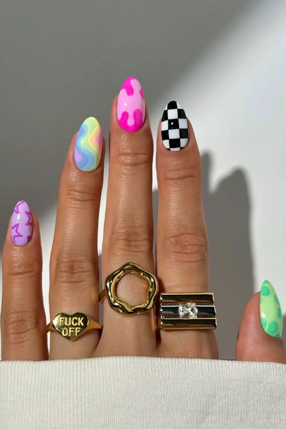 Mismatched nails featuring checkerboard, squiggles, and neon designs.