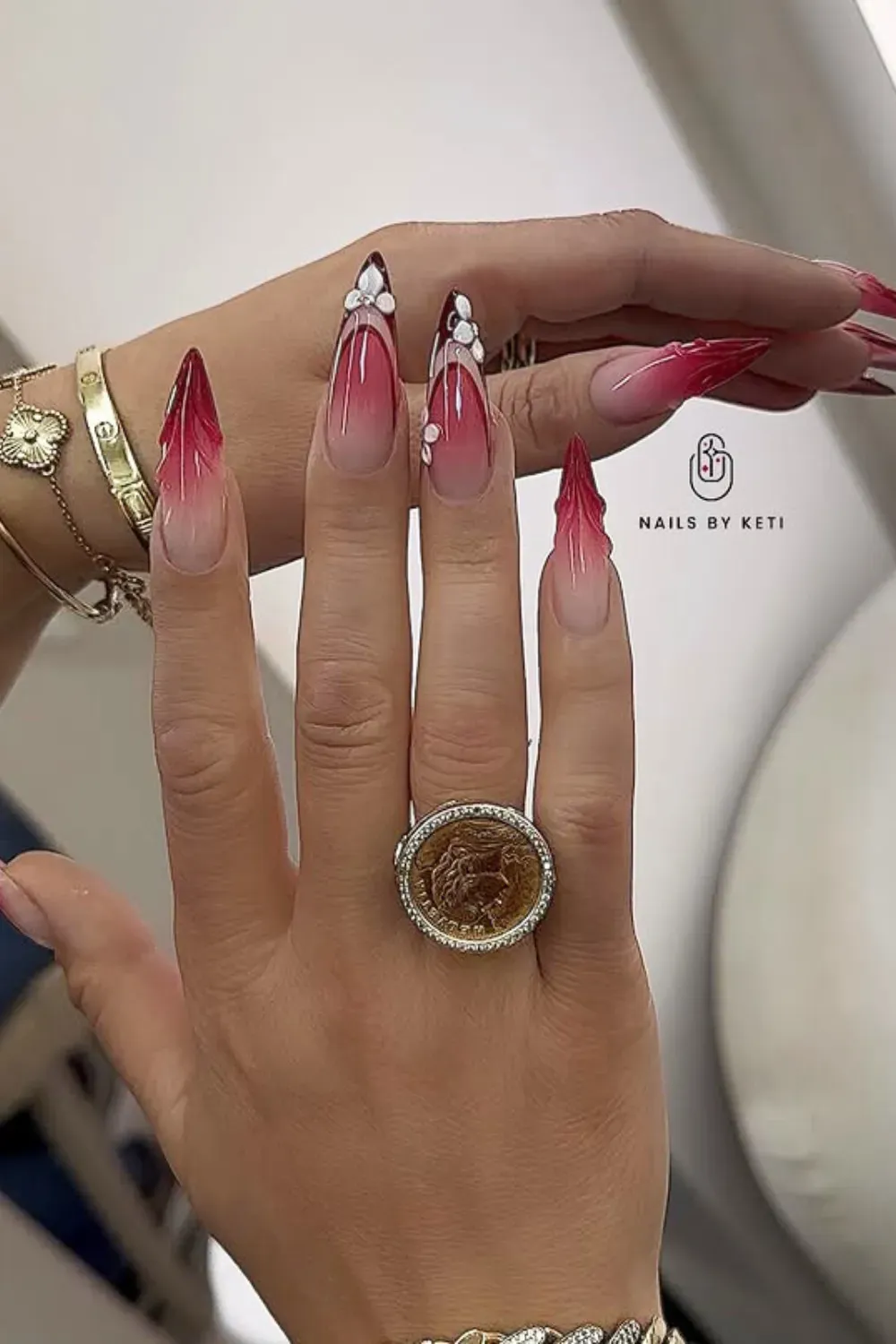 Extra-long stiletto nails featuring a nude-to-deep-red ombre with 3D flowers and sparkling crystals.