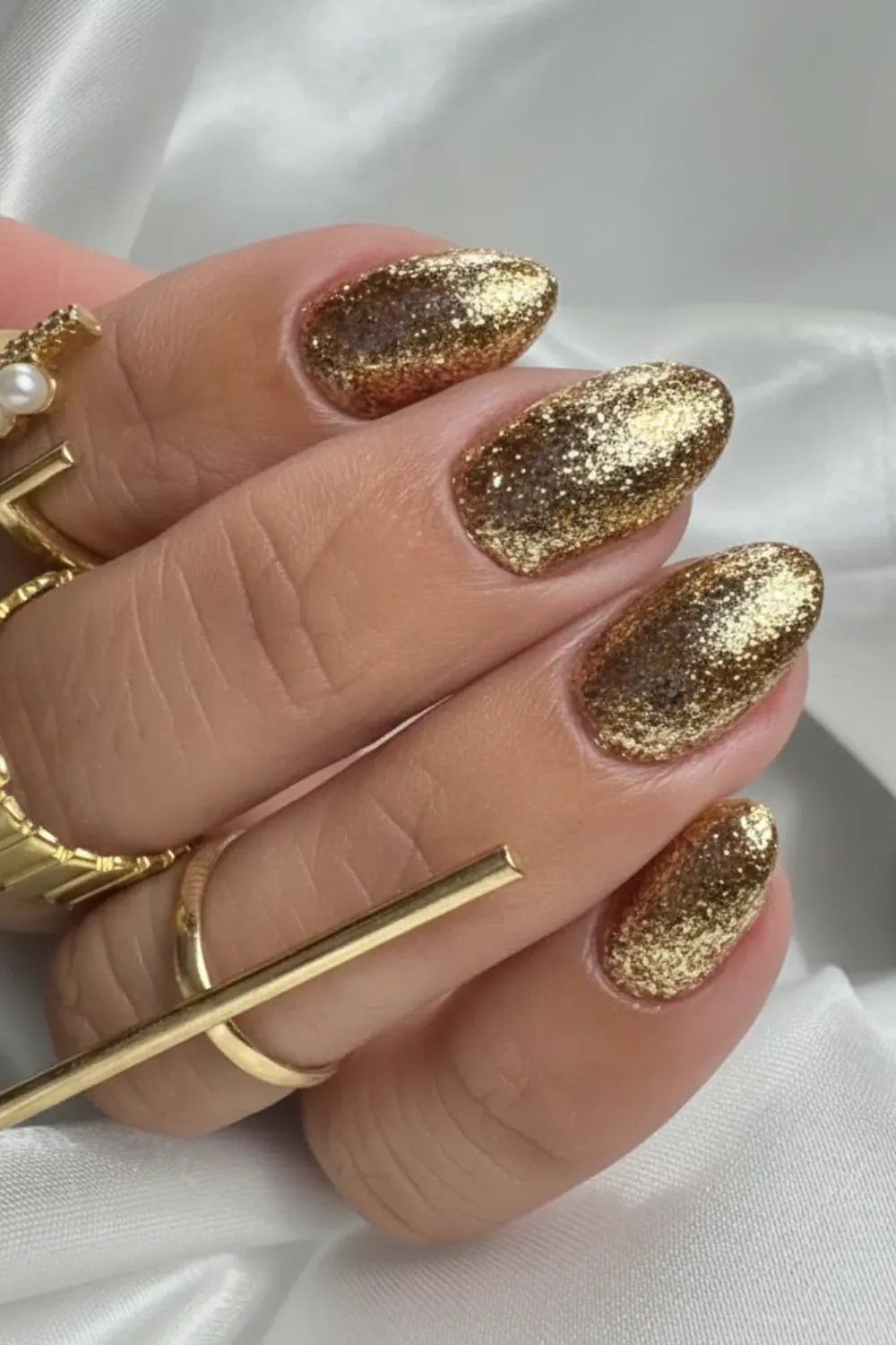 Oval nails covered in chunky gold glitter