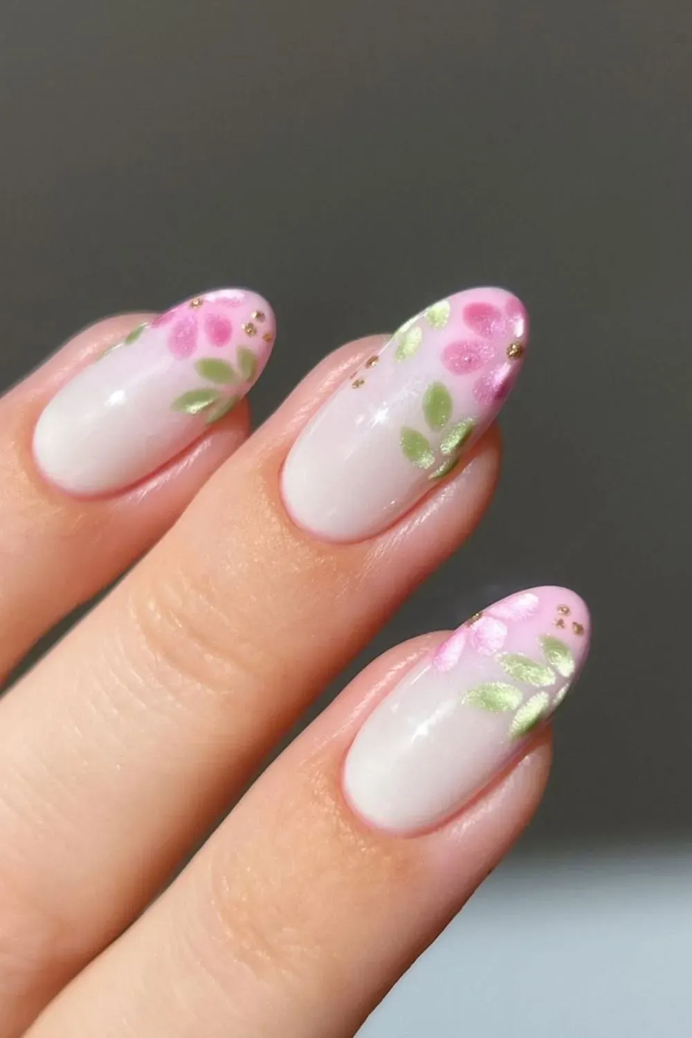 Hand-painted floral nails in pink and green on a translucent base.