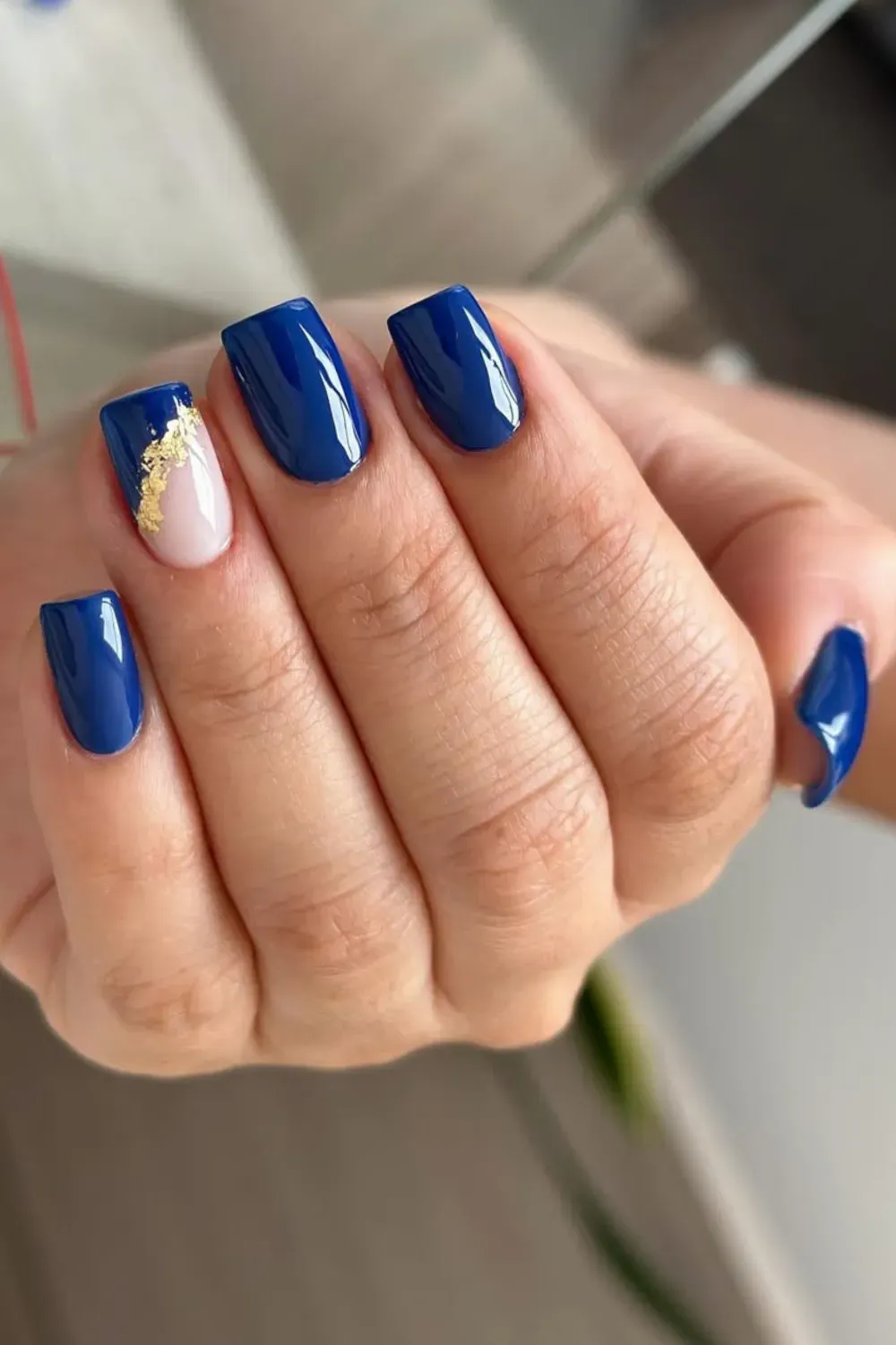 Royal Blue Square Nails with Gold Foil Accent Square nails in a glossy royal blue, with one accent nail featuring a nude base and gold foil flakes.