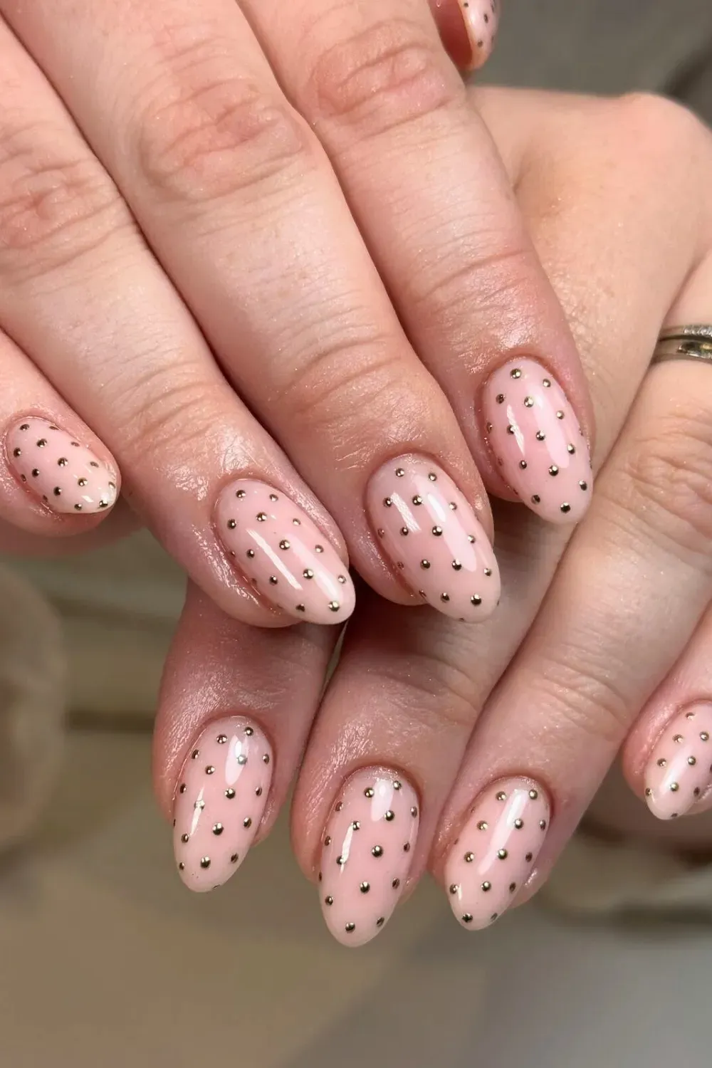Short nude nails with gold metallic polka dots.