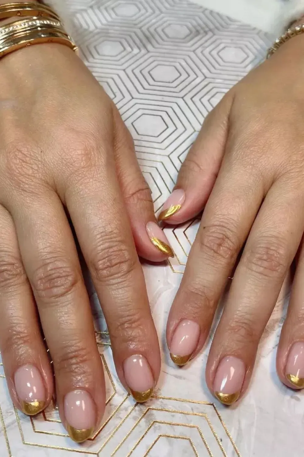 Gold-Tipped French Manicure - Nude nails with shiny gold tips on a rounded shape