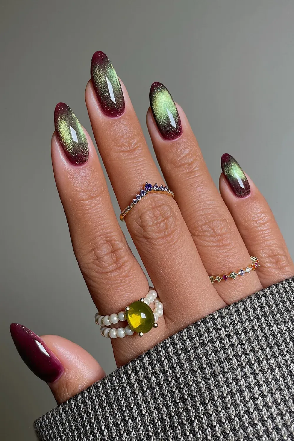 Long, oval nails featuring a duo-chrome burgundy and lime green velvet cat eye effect.