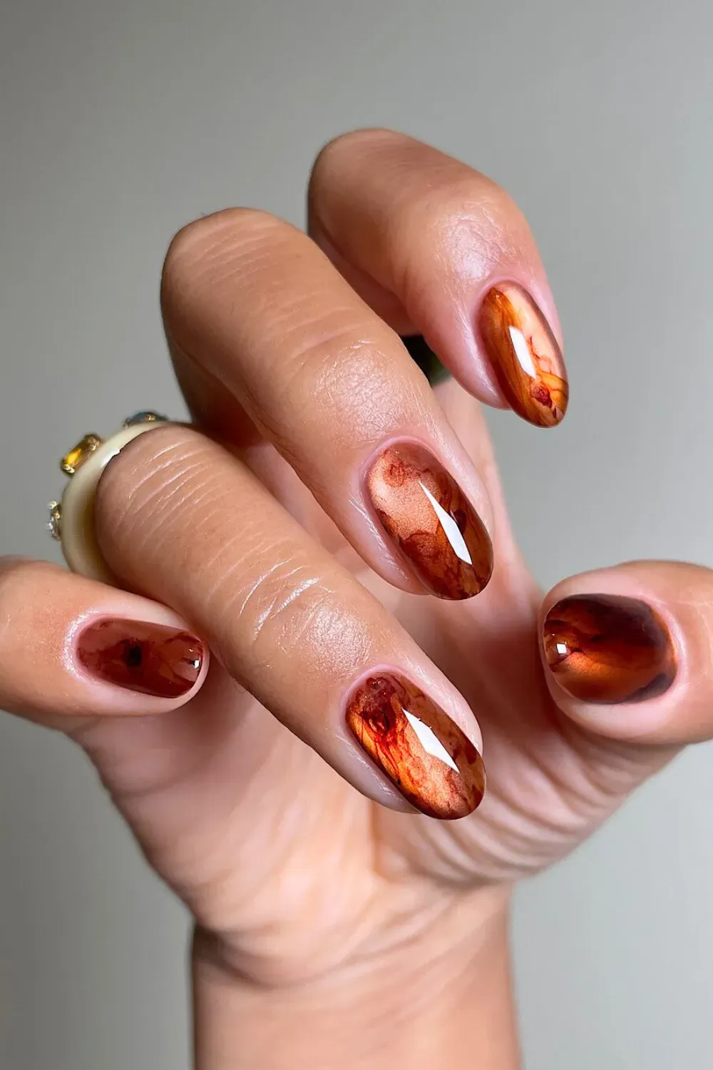 Glassy brown and amber cat eye nails with a soft, smoky coffee bloom art on short oval nails.