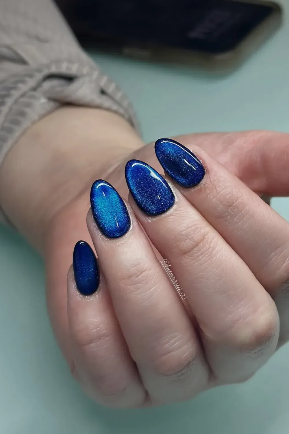 Magnetic Cat-Eye Blue Oval Nails Oval-shaped nails featuring a dynamic, shimmering magnetic cat-eye effect in a bright blue, catching the light.