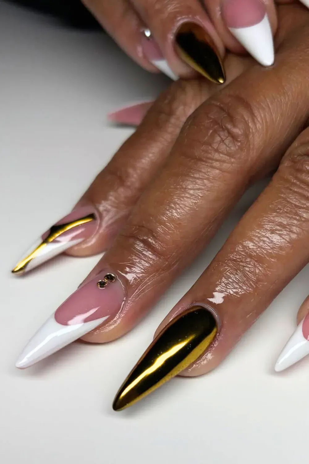 Matte gold almond nails with rhinestones at the cuticle.