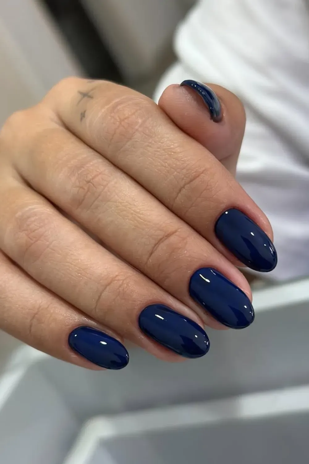 Deep Navy Blue Glossy Oval Nails - Hand with smooth, glossy, deep navy blue oval-shaped gel nails.