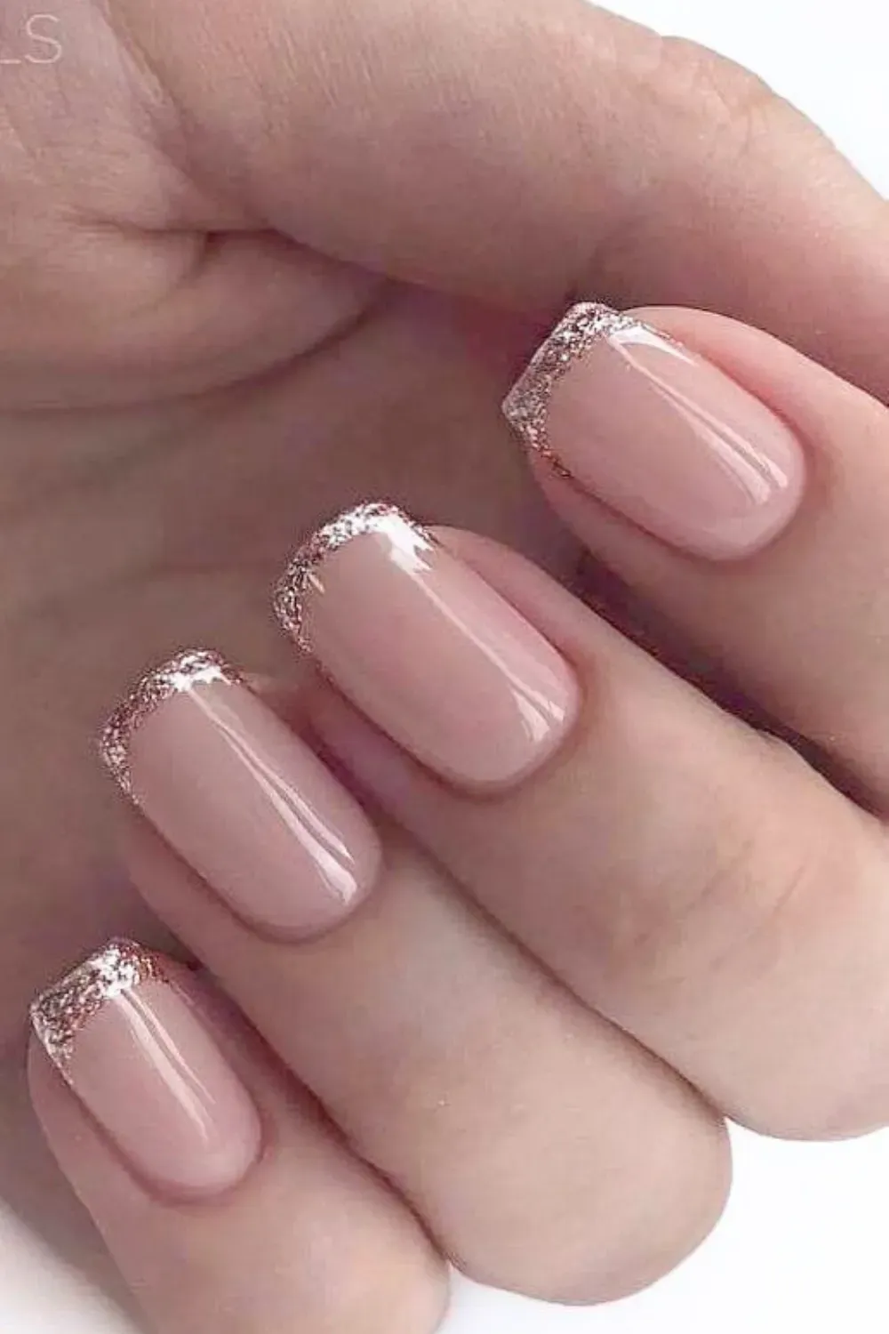 Short oval nails with a sheer pink base and a rose gold glitter micro-French tip.