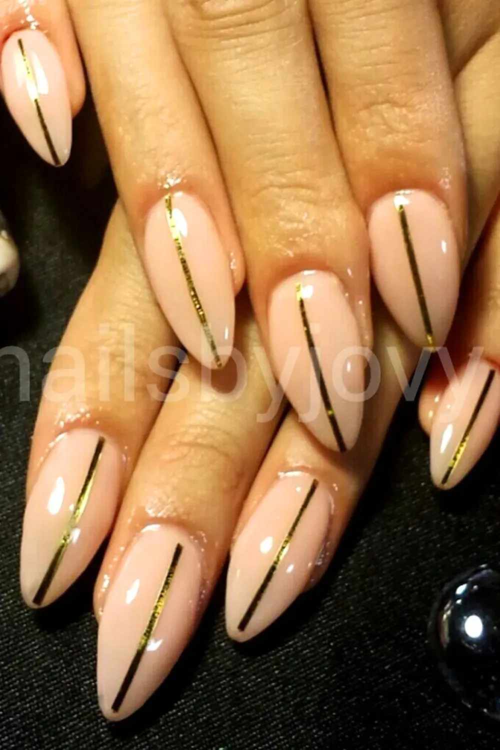 Nude nails with a thin vertical gold stripe.