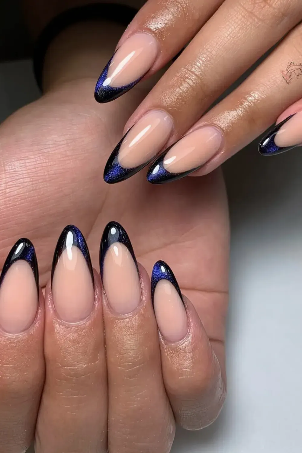 Cat-Eye Glitter Blue French Tip Stiletto Nails - Stiletto-shaped nails with a nude base and dramatic, shimmering dark blue, cat-eye effect French tips.
