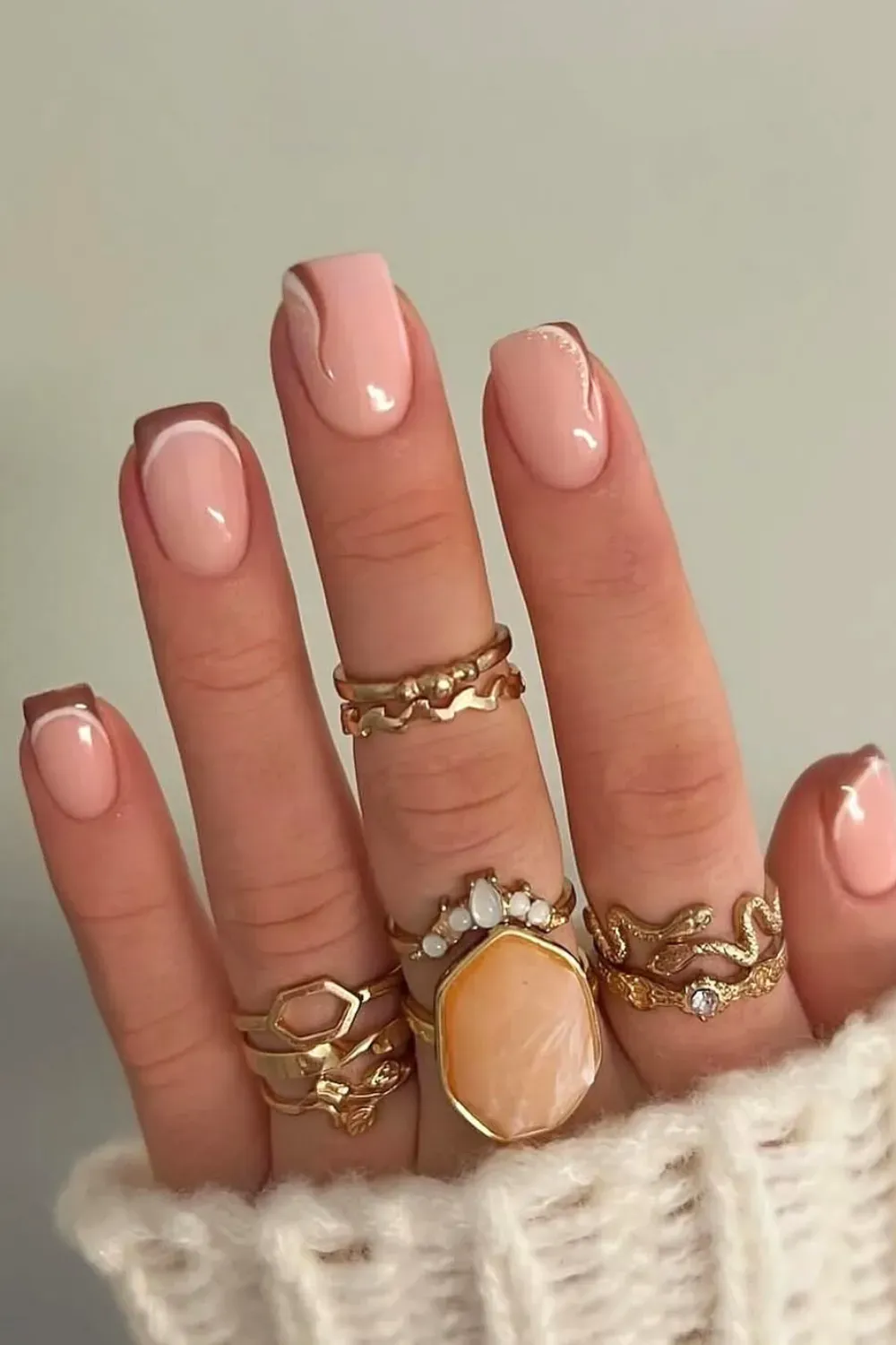 The Modern French & Abstract Art Combo: A chic French manicure with a nude base, deep chocolate brown tips, and a sleek white curved line, giving a modern and artistic flair.