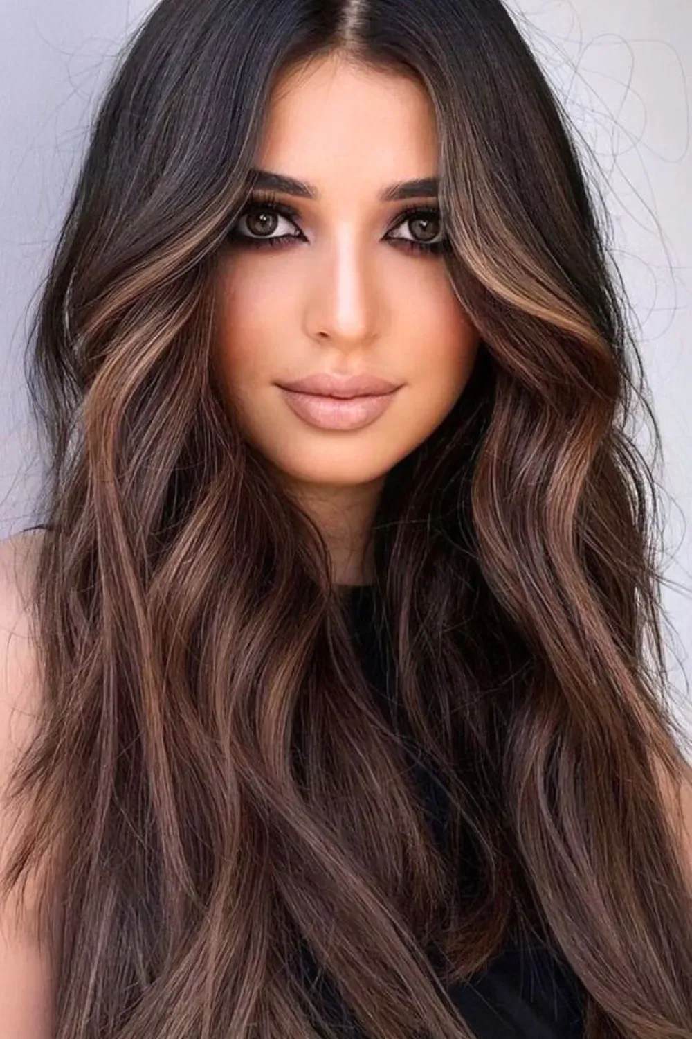 Long Wavy Honey-Caramel Balayage	Woman with long, wavy dark hair and soft, honey-caramel balayage concentrated at the ends and face.