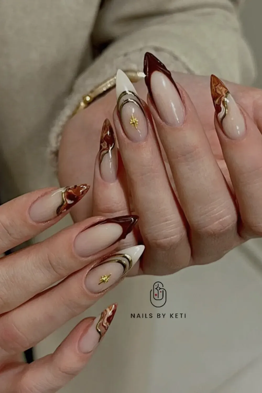 Abstract Swirl French Nails Alt Text: Earth tone abstract swirl tips with gold star charm.