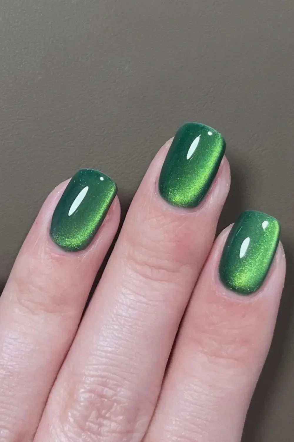 Rich emerald green cat eye nails with bright glowing center on short tips