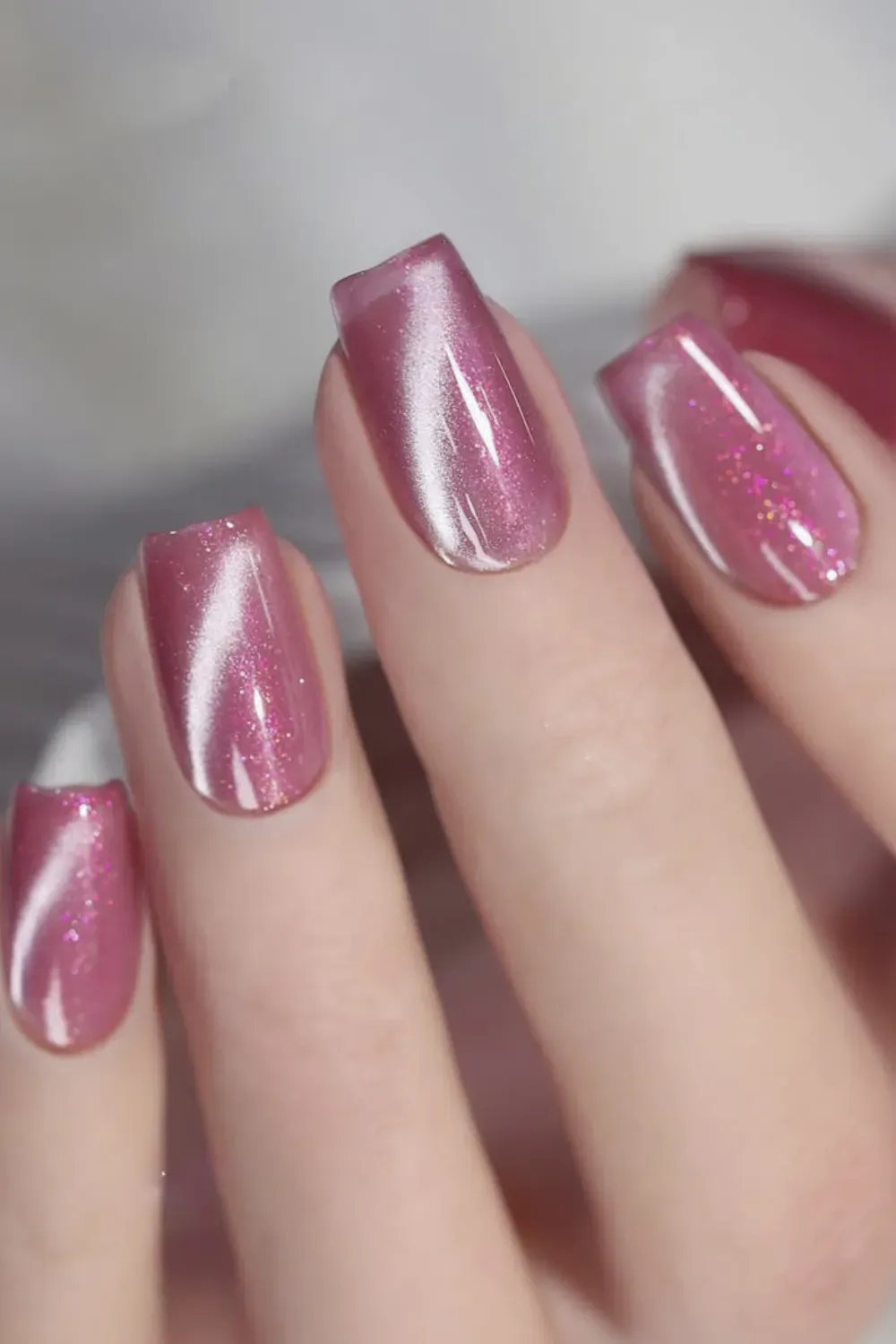 Feminine rose pink cat eye nails with added glitter sparkle on natural nails
