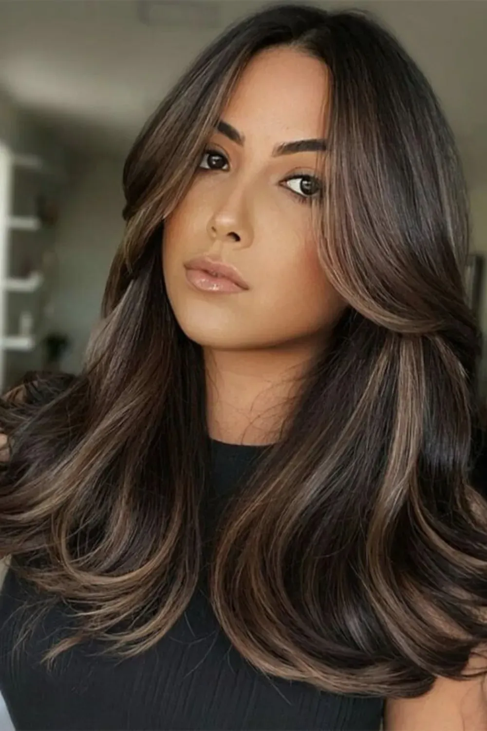 Face-Framing Caramel Balayage on Layered Curls	Woman with long, dark, layered hair featuring caramel balayage focused on the face-framing layers.
