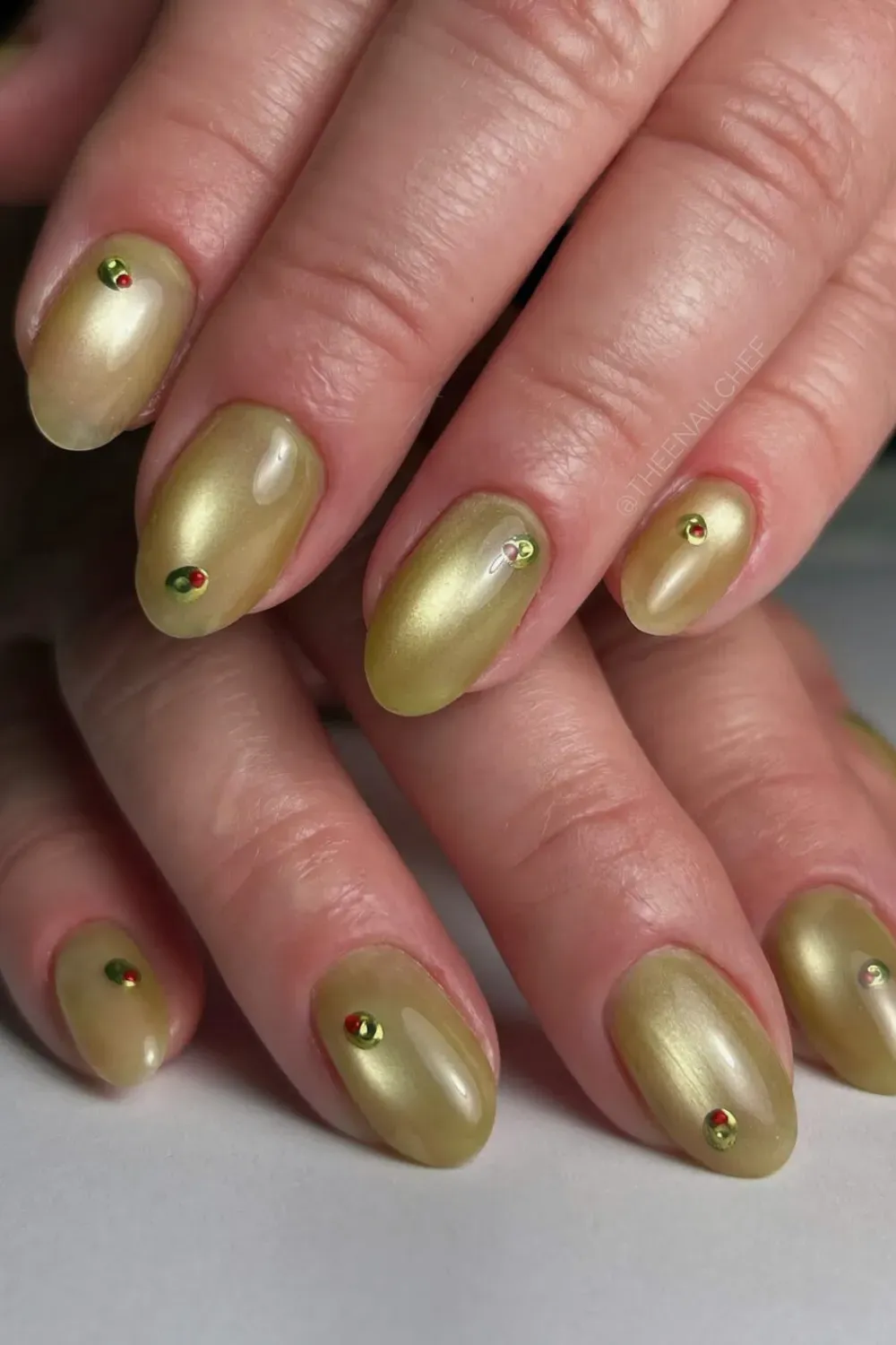 Chartreuse green golden cat eye nails with retro red and green dots on short round nails