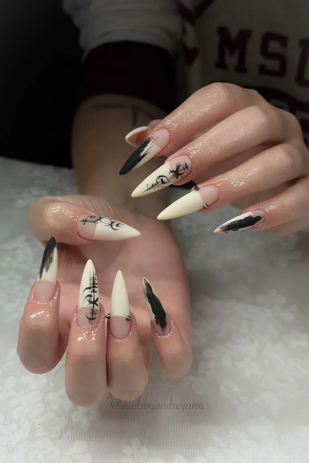 Punk Spike French Nails Alt Text: Stiletto nails with black scribbles and metal spikes on white tips.