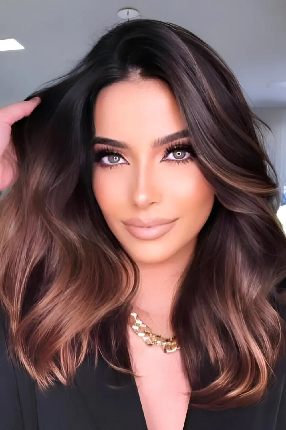 Dark Caramel Ombre on Voluminous Curls	Woman with voluminous dark brown hair and a warm caramel ombre melting into the ends.