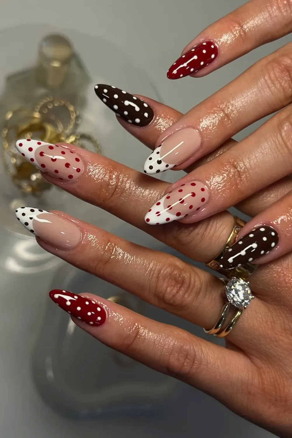 Red Brown and Nude Mix Polka Dot Nails - Almond nails featuring a mix of deep red with white dots, brown with white dots, and french tips with dots.